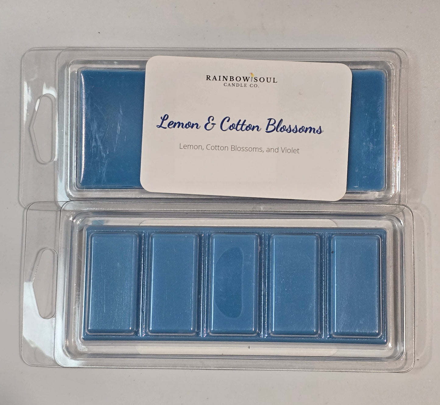 Blue wax melts in a clear plastic container with a label on a white background