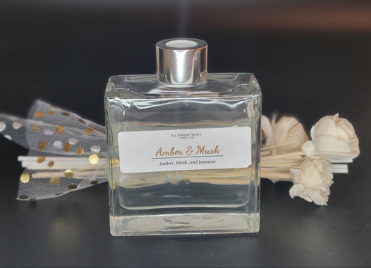 Clear diffuser bottle with silver cap and decorative flowers on a dark background